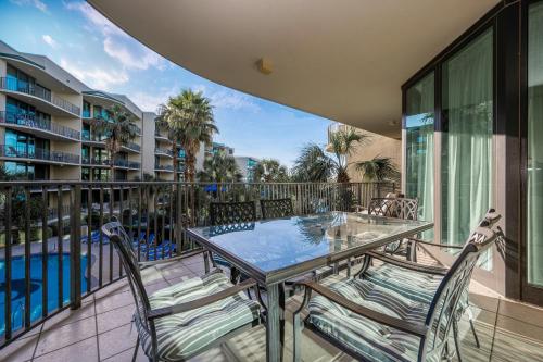 an outdoor balcony with a glass table and chairs at Phoenix on the Bay 1215 condo in Orange Beach