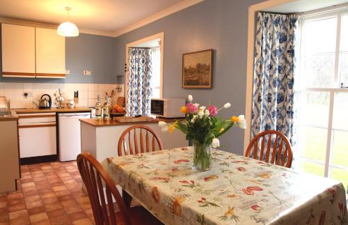 a kitchen with a table with a vase of flowers on it at Inverawe Cottages in Taynuilt