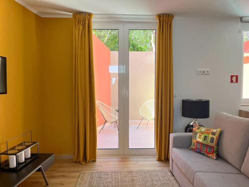 Una sala de estar con un sofá y una puerta corrediza de vidrio. en Casa Nêspera, en Lisboa