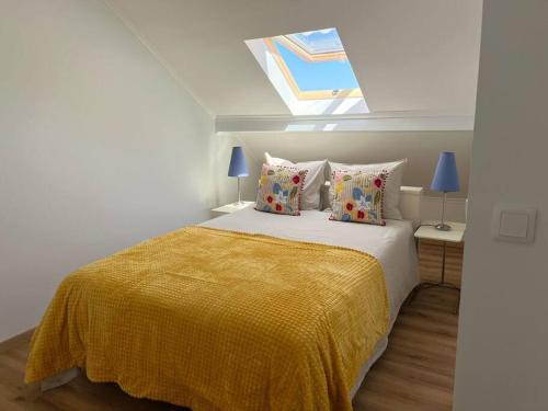1 dormitorio con 1 cama con manta amarilla y ventana en Casa Nêspera, en Lisboa