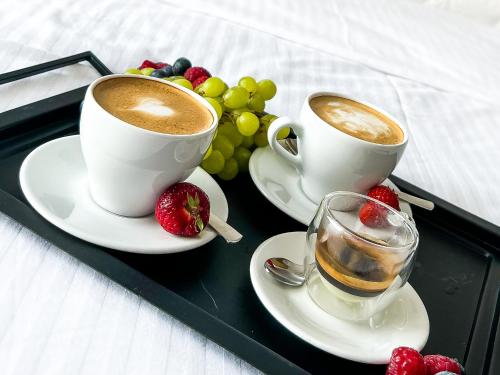 two cups of coffee and a tray of fruit at Aquarius Stawy 1 in Grodzisk Mazowiecki