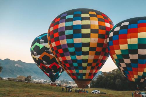 three colorful hot air balloons in a field at Pousada Equilíbrio dos Canyons in Praia Grande