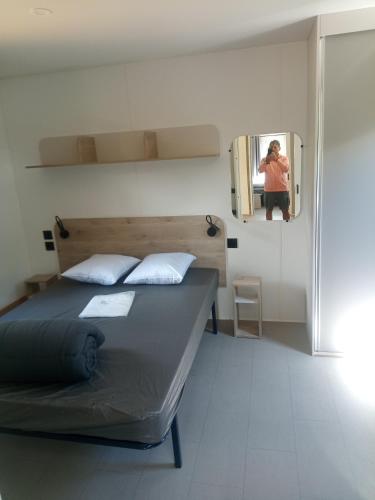 a bedroom with a bed and a mirror with a person taking a picture at Camping de Marcilly sur Vienne in Marcilly-sur-Vienne