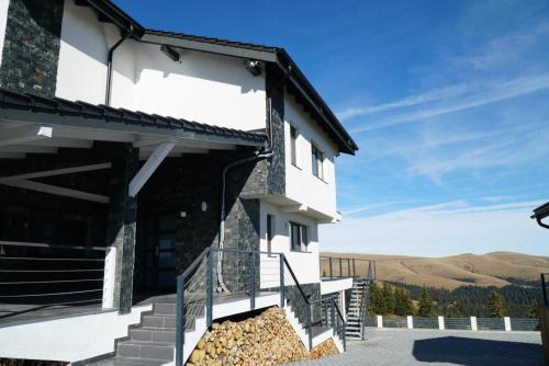 a building with stairs and mountains in the background at Alpine Blu - Horezu - Varful lui Roman - Sauna, Hot Tub & Gym in Horezu