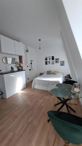 - une chambre blanche avec un lit et deux tables dans l'établissement Cozy Charming Studio with breathtaking view, à Paris