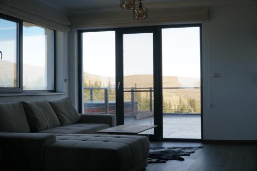 a living room with a couch and large windows at Alpine Blu - Horezu - Varful lui Roman - Sauna, Hot Tub & Gym in Horezu