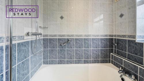 a bathroom with a tub and a shower with a sign at 3 BEDROOM SERVICED HOUSE WITH FREE PARKING FOR 2 CARS, FREE WiFi, PERFECT FOR BUSINESS STAYS, FAMILIES, RELOCATIONS, EXTENDED STAYS, AND EMERGENCY ACCOMMODATION by REDWOOD STAYS in Camberley
