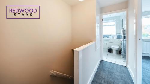 a bathroom with a toilet and a stairwell with a sign at 3 BEDROOM SERVICED HOUSE WITH FREE PARKING FOR 2 CARS, FREE WiFi, PERFECT FOR BUSINESS STAYS, FAMILIES, RELOCATIONS, EXTENDED STAYS, AND EMERGENCY ACCOMMODATION by REDWOOD STAYS in Camberley