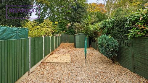 a garden with a fence and a yard with leaves at 3 BEDROOM SERVICED HOUSE WITH FREE PARKING FOR 2 CARS, FREE WiFi, PERFECT FOR BUSINESS STAYS, FAMILIES, RELOCATIONS, EXTENDED STAYS, AND EMERGENCY ACCOMMODATION by REDWOOD STAYS in Camberley