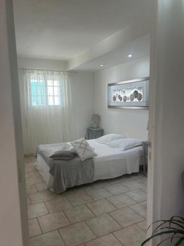 a bedroom with a white bed and a window at F2 de charme Les Abymes in Les Abymes