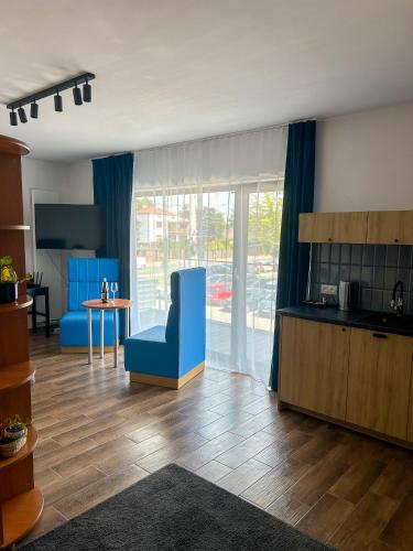 a living room with a blue chair and a kitchen at Aquarius Stawy 3 in Grodzisk Mazowiecki
