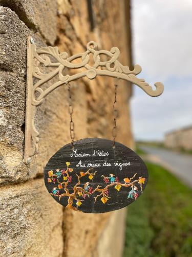 un panneau suspendu sur le côté d'un mur de pierre dans l'établissement Au creux des vignes, à Les Verchers-sur-Layon