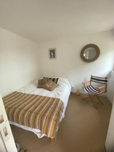 une chambre avec un lit, un miroir et une chaise dans l'établissement Gîte Traou Nod, à Pleudaniel