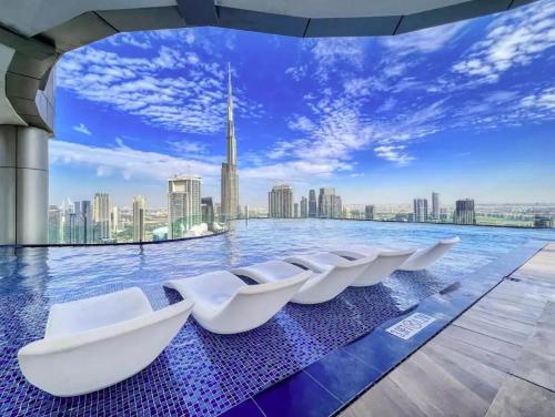 a pool with white chairs on the roof of a building at WonderfulStay at Paramount Residences - Highest Infinity Pool - Burj Khalifa View - Brand New Luxury Apartments in Dubai