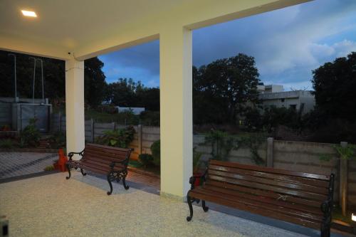two benches sitting on a patio with a view at PRS CREEK SIDE HOME STAY VILLA in Yelagiri