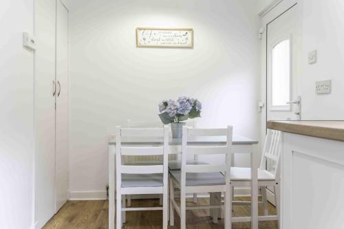 Un comedor blanco con una mesa y sillas. en Glentarbet House, en Glasgow