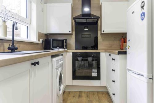 a kitchen with white cabinets and a stove top oven at Glentarbet House in Glasgow