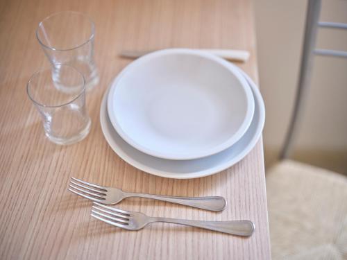 a table with a plate and two forks and glasses at RESIDENCE Leccio in Asciano