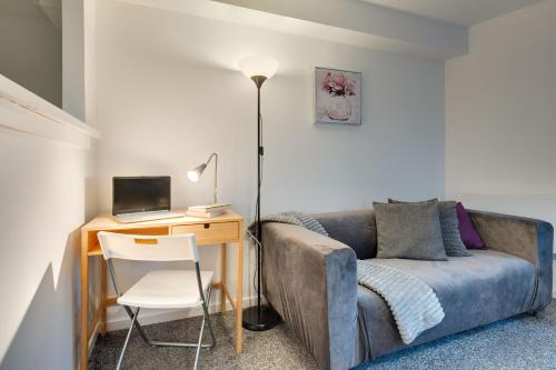 a room with a desk with a couch and a laptop at Central 3 bedroom Apartment & Free Parking- Ideal 4 long stays in Newcastle upon Tyne