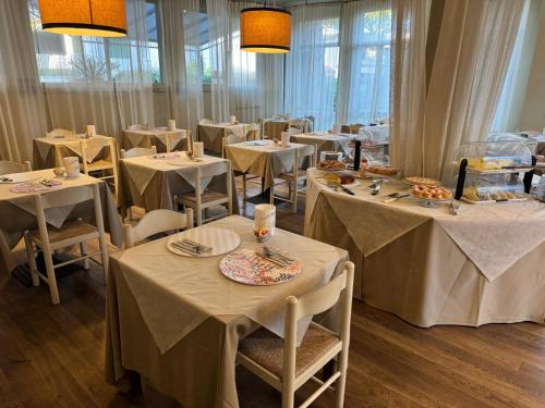 a dining room with white tables and chairs at Hotel Le Focette in Marina di Pietrasanta