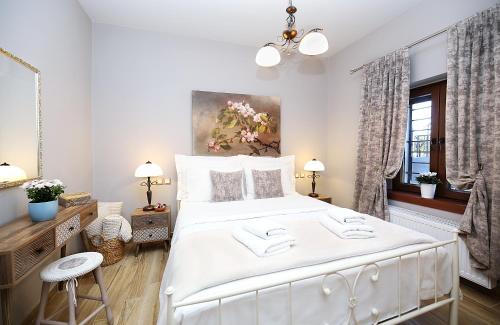 a white bedroom with a white bed and a painting at VENUS GUESTHOUSE in Portariá
