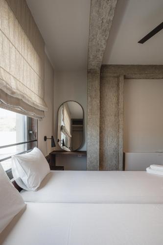 a bedroom with a large white bed and a mirror at Nima Residences in Paleros