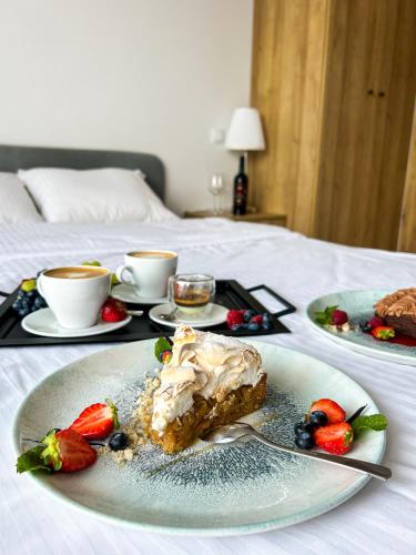 a piece of cake on a plate with fruit on a bed at Aquarius Stawy Walczewskiego 6 in Grodzisk Mazowiecki