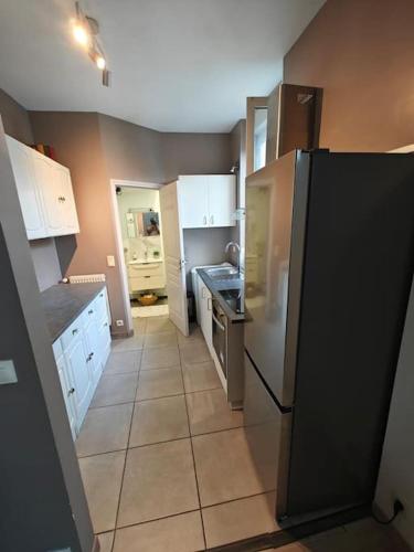 a kitchen with white cabinets and a black refrigerator at Celine Appart in Cormontreuil