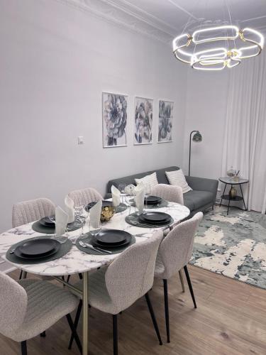 un salon avec une table avec des chaises et un canapé dans l'établissement Le Rapp 6, Appartement de Standing 3 chambres, 7 personnes &1 bébé, Cosy et familial ultra équipé Emplacement Idéal proche Gare Centre ville Marchés de Noël Quartier Tribunal Contades, à Strasbourg