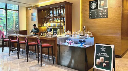 a bar in a restaurant with a woman behind a counter at Holiday Inn & Suites Makati by IHG in Manila