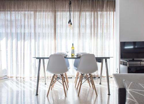 a dining room table with white chairs and a bottle of wine at Lux Downtown Sea View Apartment D3 in Thessaloniki