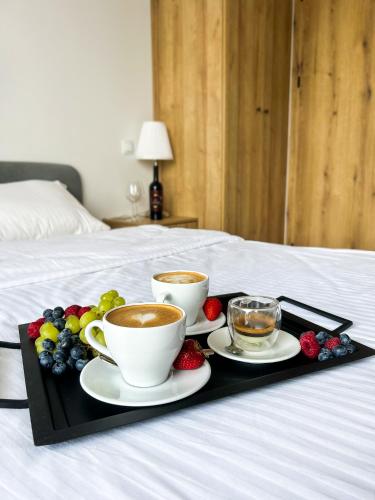 a tray with two cups of coffee and fruit on a bed at Aquarius Stawy Walczewskiego 8 in Grodzisk Mazowiecki