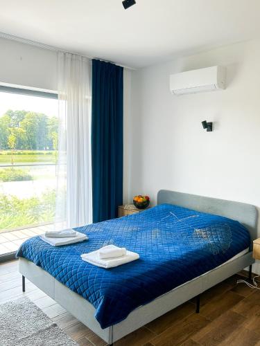 a bedroom with a blue bed with two towels on it at Aquarius Stawy Walczewskiego 8 in Grodzisk Mazowiecki