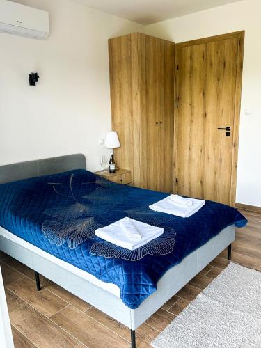 a bedroom with a blue bed with towels on it at Aquarius Stawy Walczewskiego 8 in Grodzisk Mazowiecki