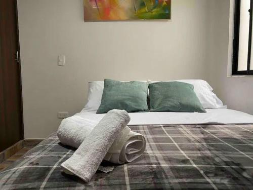 a white bed with green pillows in a room at Apartamento en Envigado al Sur de Medellin in Envigado