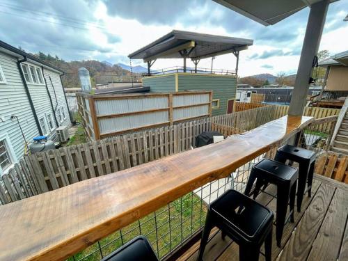 a deck with a wooden bar and stools at Urban Retreat Downtown Gem Walk Everywhere Train View Mountain View Near National Park Entrance in Bryson City