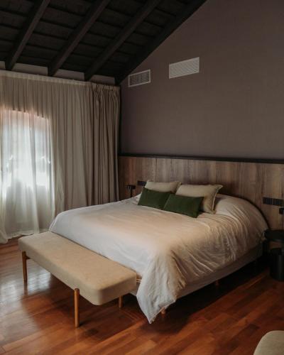 a bedroom with a white bed with a bench and a window at Casa Toledo in La Cumbre