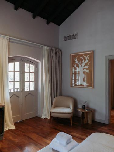 a bedroom with a bed and a chair and a window at Casa Toledo in La Cumbre