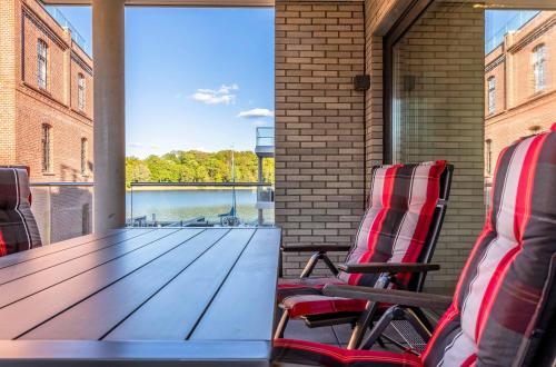 a table and chairs on a balcony with a view of the water at Pusteblume - Barrierefreie 5-Sterne-Ferienwohnung mit Seeblick und Sauna in Malchow