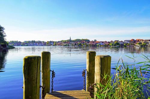 a dock on a lake with houses in the background at Pusteblume - Barrierefreie 5-Sterne-Ferienwohnung mit Seeblick und Sauna in Malchow