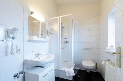 un bagno bianco con lavandino e WC di Kietz-Idylle - Gemütliche Ferienwohnung mit Balkon und Zugang zu Wellnessbereich a Waren