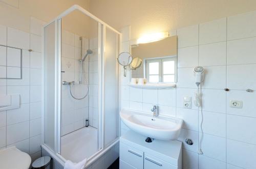 a white bathroom with a sink and a shower at Kietz-Perle mit Balkon & Müritzblick im historischen Speicher in Waren
