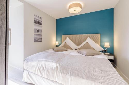 Un dormitorio con una cama blanca con una pared azul. en Lüttkoje - Ferienwohnung mit zwei Schlafzimmern, en Wustrow