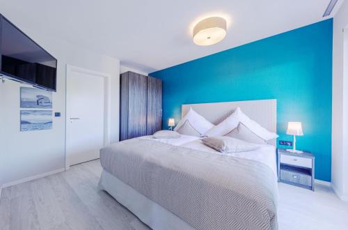a bedroom with a large bed with a blue wall at Strandluft - 5 Sterne Ferienwohnung mit Infrarotkabine in Wustrow