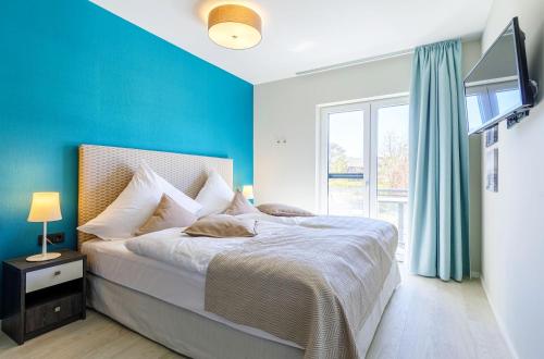 ein Schlafzimmer mit einem Bett und einer blauen Wand in der Unterkunft Swantovit - 5 Sterne Ferienwohnung zwischen Ostsee und Saaler Bodde in Wustrow