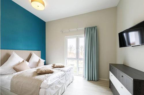 a bedroom with a bed with blue walls and a television at Boddentraum - 5 Sterne Ferienwohnung mit Blick auf das malerische Ostseebad Wustrow in Wustrow