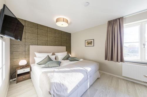 a bedroom with a bed and a flat screen tv at Boddendomizil - stilvoll wohnen, am Meer entspannen, Strandkorb genießen in Wustrow