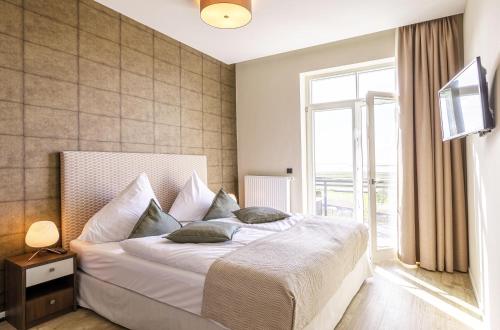 a bedroom with a large white bed with a window at Ostseeglück - 5-Sterne-Ferienwohnung mit Südbalkon und Blick zum Saaler Bodden in Wustrow