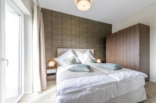 a bedroom with a large white bed with blue pillows at Störtebeker Suite 5-Sterne-Urlaub an der Ostsee in Wustrow