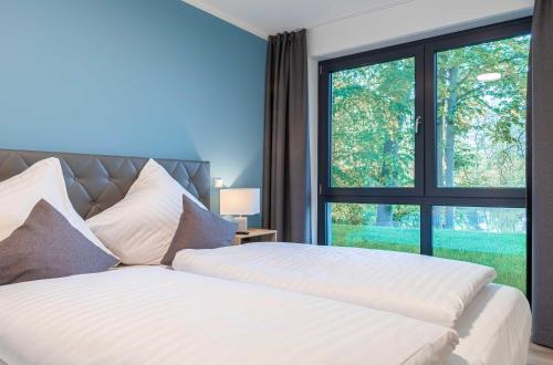 a bedroom with two beds and a large window at Lotusblume - 5 Sterne Ferienunterkunft mit möblierter Terrasse am Krakower See in Krakow am See